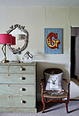 PInk lamp and mirror with chest and artwork of letter 'G' in Devon home, UK