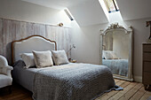 Light grey woollen blanket on double bed with full length vintage mirror in West Sussex home, UK