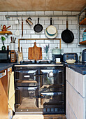 Grauer Ofen und Pfannenständer in kleiner Küche eines umgebauten Schiffscontainers Bedford, UK