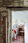 View through exposed stone doorway to bed in renovated Yorkshire farmhouse, UK