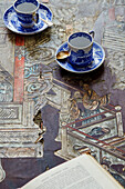 Cups and saucers on chipped oriental tabletop in Foix, Ariege, France