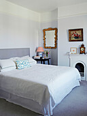 Decorative mirror and double bed with white embroidered linen in Northern home, UK