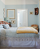 Vintage lace bed cover with yellow quilt in light blue bedroom of Northern home, UK