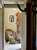 Wicker chair and basket with framed print of Queen Elizabeth in doorway of Oxfordshire farmhouse, UK