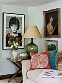 Lamp on side table with framed artwork in Oxfordshire farmhouse, UK