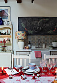 Happy Christmas' auf einer Tafel über dem Waschbecken mit Gläsern und Geschirr auf dem Tisch