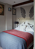 Angel wings above double bed with with linen pillows and pastel blue and pink covers