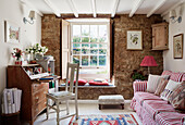 Red and white striped sofa and writing desk with window seat in old stone cottage, UK