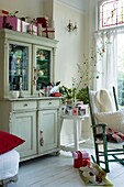 Wohnzimmer mit Schaukelstuhl, Weihnachtsdekoration und Weihnachtsgeschenken auf dem Schrank