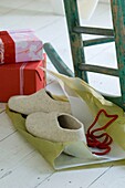 Slippers on white wooden floor on wrapping paper and two wrapped Christmas presents
