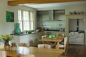 Kitchen with stove behind table with vegetables and flowers