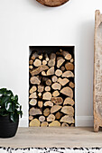 Firewood stacked in alcove in Reigate living room, Surrey, UK