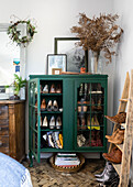 Upcycled glass display cabinet shoe storage with dried ferns in Colchester bedroom Essex, UK