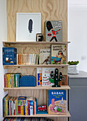 Sperrholzregal mit Büchern und Spielzeug in einem Jungenzimmer in Colchester, Essex, UK