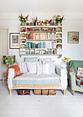 Flowers and books on wall-mounted second-hand bookshelf Brighton, East Sussex UK