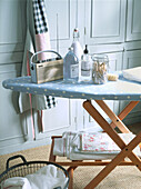 Wooden ironing board with pale blue and white spotted cover in laundry room