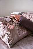 Bedroom detail with floral cushions in tones of pink and purple