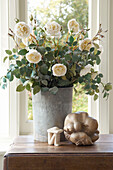 Cut flowers with ornaments on side table at window of Canterbury home England UK