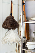 Feather dusters and brushes hang on back of door in Hastings home, East Sussex, England, UK