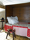 Book and candle on stool beside bed