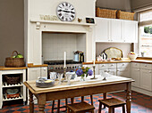 Crockery and wineglasses in kitchen with roman clock above recessed oven in Hereford, England, UK
