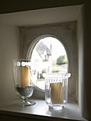 Glass candle holders at oval shaped window of Gloucestershire farmhouse, England, UK