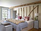 Geblümte Steppdecke auf einem Bett in einem Zimmer mit Holzrahmen und hellblauem Anstrich in einem Bauernhaus in Gloucestershire, England, UK