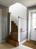 Grey wall panelling and wooden staircase in hallway entrance of Hampshire farmhouse, England, UK