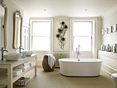 Freistehende Badewanne mit geblümten Wänden und Doppelwaschbecken im Badezimmer eines modernen Hauses in Bath, Somerset, England, UK