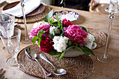 Rosafarbene und weiße Blumendekoration mit Gläsern auf dem Esszimmertisch in einem Landhaus in Suffolk, England, UK