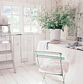 White washed panelled garden studio workshop with desk and linen table cloth