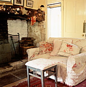 Country style living room with floral fabric sofa foot stool and inglenook fireplace