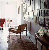 Display of old family black white and sepia photographs hung on a wall in an upstairs hallway with armchair and floor rugs