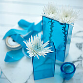 Detail von türkisblauen Glasvasen mit weißen Chrysanthemenblüten