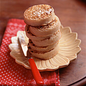 Hot buttered crumpet cakes stacked on a plate on wooden tabletop