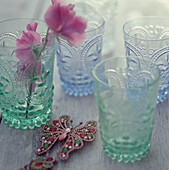 Four green and blue coloured glasses on a wooden tabletop
