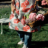 Frau in ihrem Garten sammelt Blumen in einem Korb
