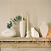 Detail von weißen Vasen und Weihnachtsschmuck auf einem hölzernen Kaminsims