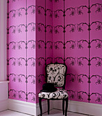 Raum mit rosa gemusterter Tapete und gepolstertem Stuhl
