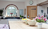 Obstschalen auf hölzernem Küchentisch mit gewölbtem Fenster in einem Landhaus in Surrey England UK