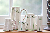 Green and white ceramic jugs on windowsill of Surrey cottage England UK