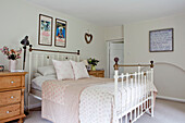 Brass bed and artwork with wooden chests of drawers in Surrey cottage England UK