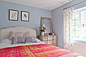 Red embroidered bed cover in blue bedroom of Surrey cottage England UK