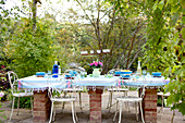 Table on brick supports with wrought iron chairs on garden terrace of Surrey cottage England UK