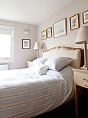 Striped duvet and bedside lamps with artwork in bedroom of contemporary Chelsea home London UK