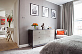 Comfortable double bedroom in soft grey with bright orange details