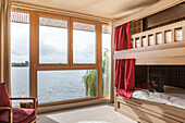 Bunkbed with red curtain at picture window in Lakes home, England, UK