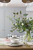 Flowers and bowls on table with runner in London home UK