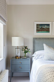 Framed prints above double bed with light blue bedside cabinet in London home UK
