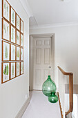 Framed leaves and green glass vases on landing in London home UK